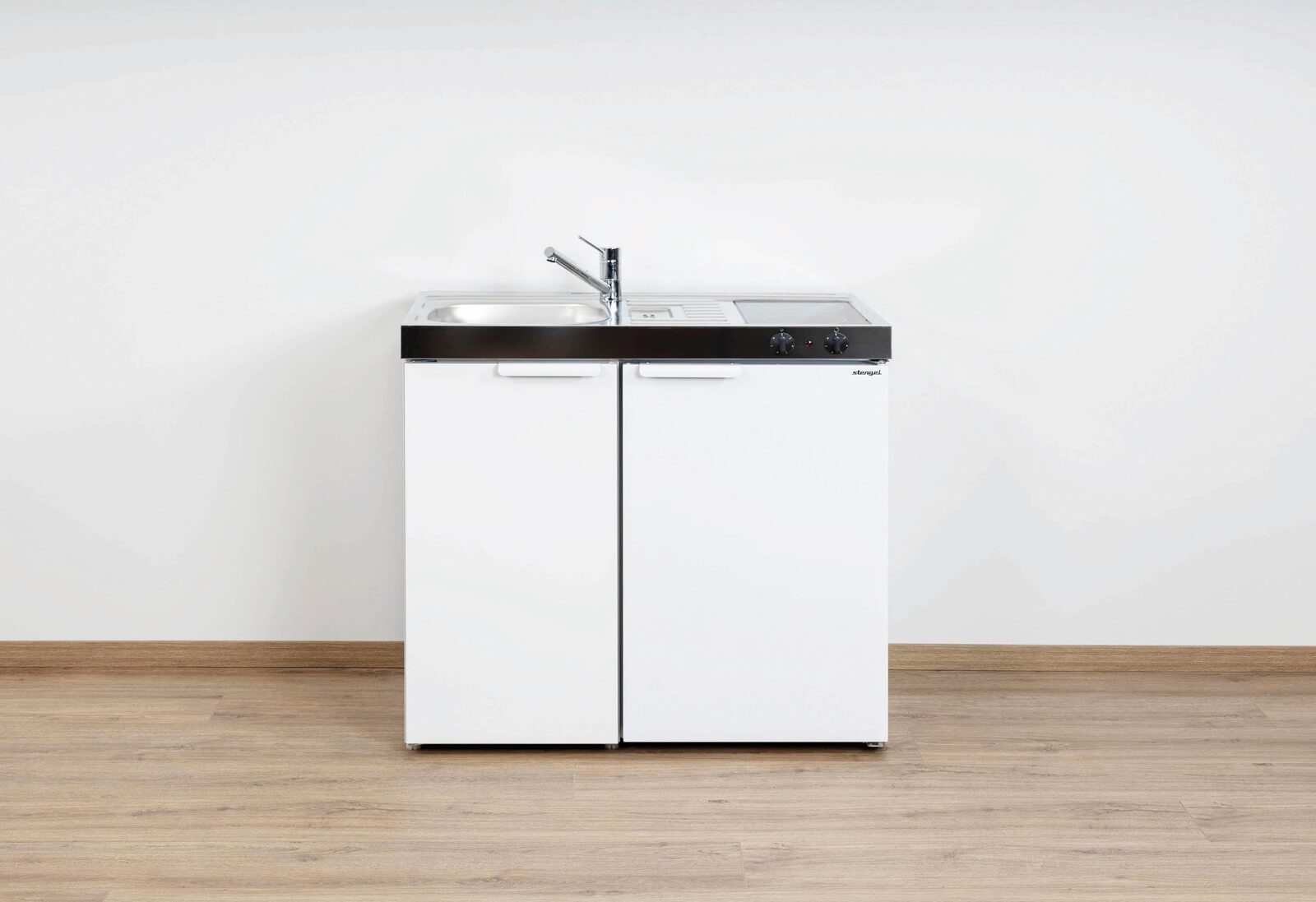 Compacte keuken met koelkast, spoelbak en kookplaat in de kleur wit.