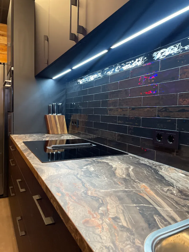 Een keuken(huur) met een zwart aanrechtblad en RVS apparatuur.