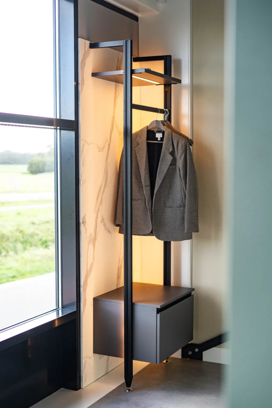 Een rek met een jas die voor een raam hangt in een kantoorkeuken in Nijkerk.