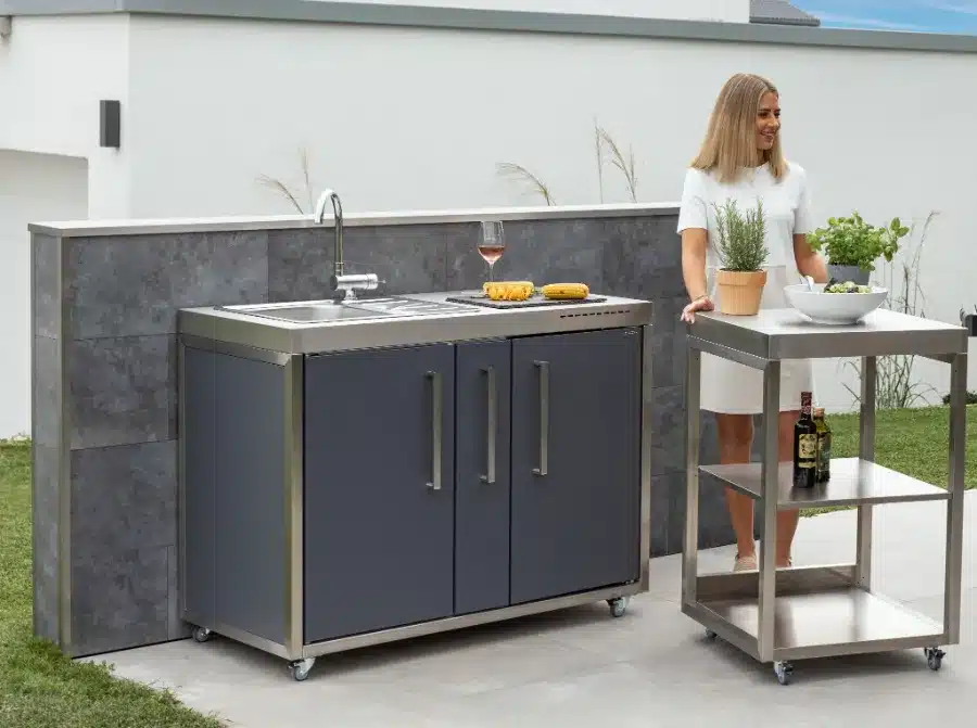 Een vrouw die naast een roestvrijstalen buitenkeuken staat.