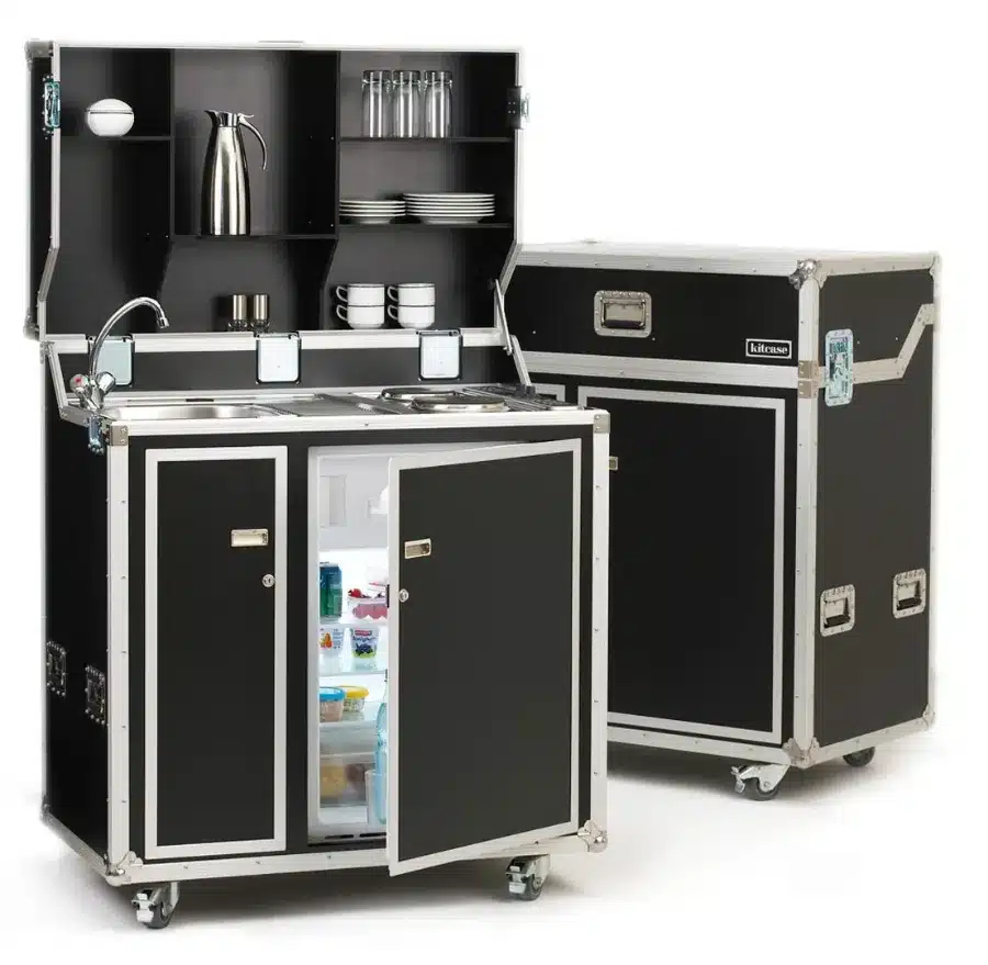 Een keuken op het werk met een zwarte kast, spoelbak en koelkast.